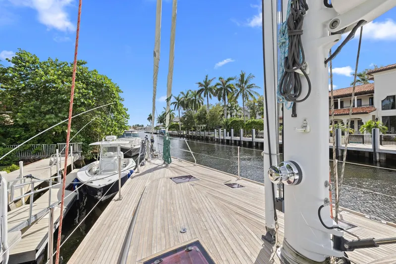 Blue Star Yacht Photos Pics Sailboat docked in a scenic canal, surrounded by palm trees and luxury homes.