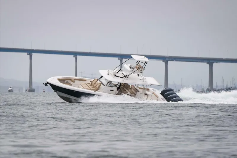 Mad Hatter Yacht Photos Pics 2019 Everglades 435 Center Console boat cruising on water near a bridge.