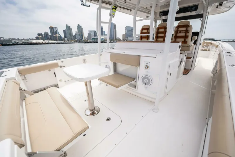 Mad Hatter Yacht Photos Pics 2019 Everglades 435 Center Console boat interior with seating and table, docked near city skyline.