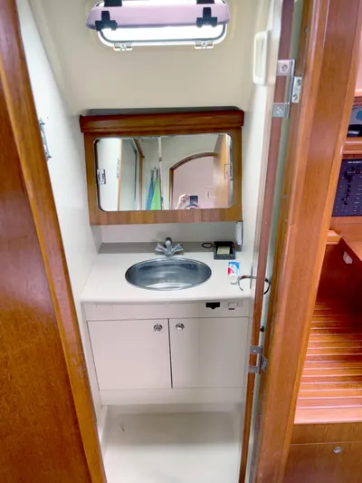 Wild Card Yacht Photos Pics Compact bathroom in 2005 Hunter 38 sailboat with sink, mirror, and wooden cabinetry.