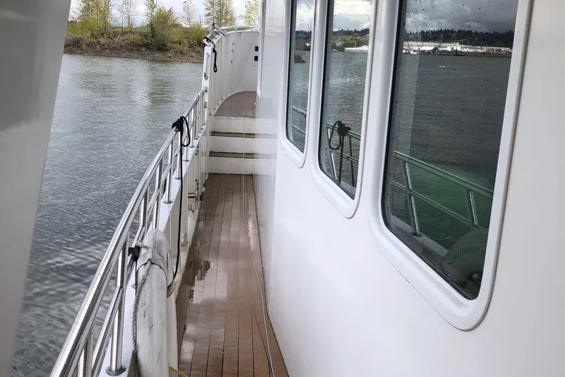 Evening Star Yacht Photos Pics 2003 Cape Horn Trawler deck with railing, overlooking calm water and shoreline.