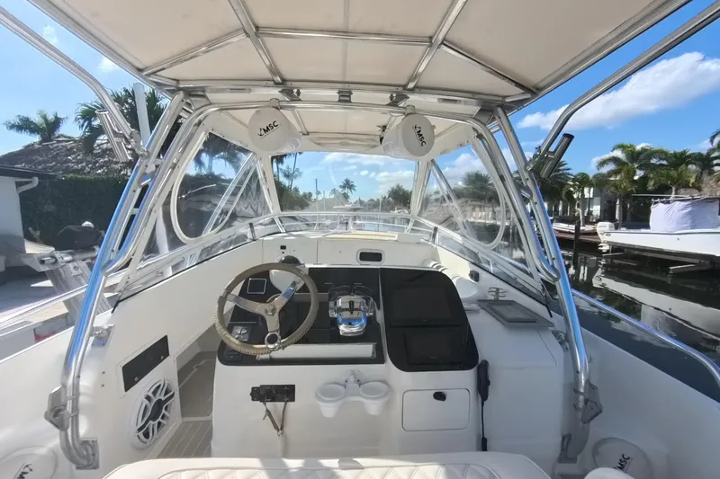  Yacht Photos Pics 2005 Intrepid 348 Walkaround boat interior with steering wheel and controls, docked by palm trees.