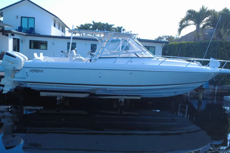  Yacht Photos Pics 2005 Intrepid 348 Walkaround boat docked near a modern house with palm trees.
