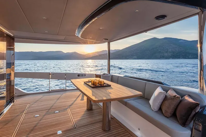  Yacht Photos Pics Manufacturer Provided Image: Luxury deck of 2022 Absolute 64 Navetta yacht at sunset, with scenic ocean and mountain views.