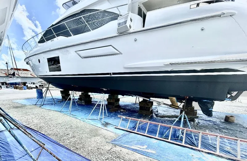 Kara Mia II Yacht Photos Pics 2019 Azimut 55 Motor Yacht on dry dock, supported by stands, under a clear sky.