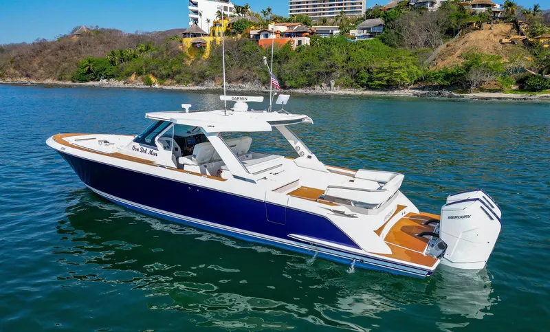 Oso Del Mar Yacht Photos Pics 2022 Tiara Yachts 43 LS boat on calm water near a scenic shoreline.