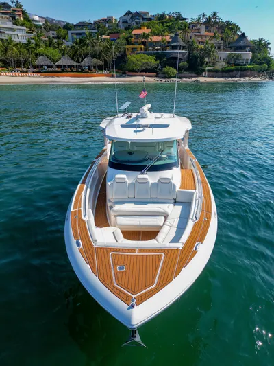 Oso Del Mar Yacht Photos Pics 2022 Tiara Yachts 43 LS on serene water near a tropical shoreline.