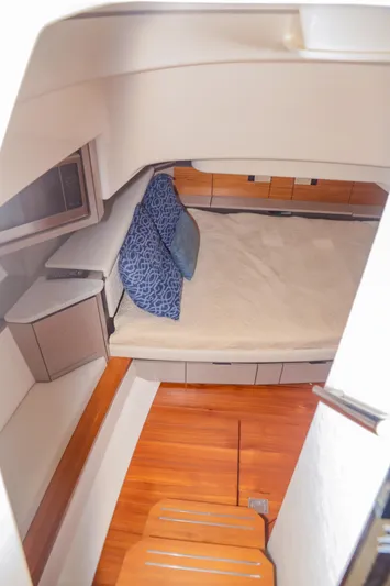 Oso Del Mar Yacht Photos Pics 2022 Tiara Yachts 43 LS cabin interior with bed and blue pillows.