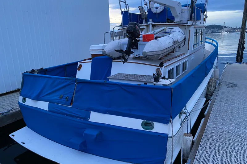 Yacht Photos Pics 1981 Grand Banks Classic Tri-cabin boat docked, featuring blue covers and a dinghy on deck.