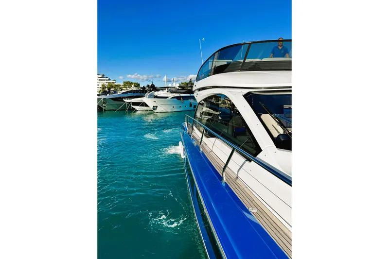  Yacht Photos Pics 2024 Azimut Fly 53 yacht cruising in a vibrant marina under clear blue skies.