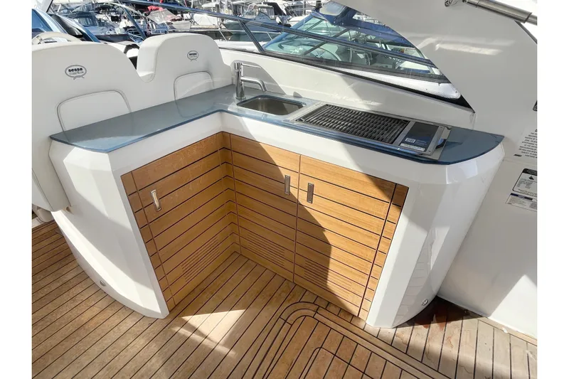  Yacht Photos Pics 2024 Sessa Marine C38 yacht kitchenette with sink and grill, featuring wooden cabinetry.