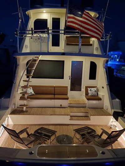 Miss Pearl Yacht Photos Pics 1989 Hatteras 65 Enclosed Bridge yacht with American flag, illuminated deck, and seating area.