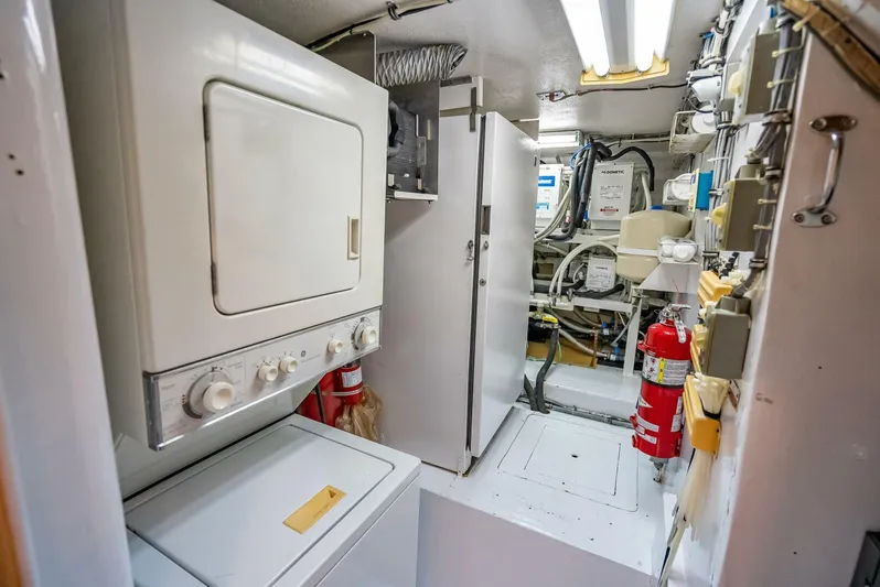 Miss Pearl Yacht Photos Pics Laundry area in 1989 Hatteras 65 Enclosed Bridge yacht with washer, dryer, and fire extinguisher.