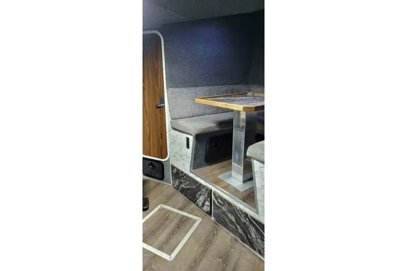 Alliance Yacht Photos Pics Interior of 2022 Custom Freestyle Marine 32, featuring a cozy seating area with a wooden table.