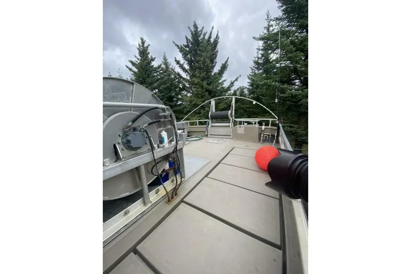 Alliance Yacht Photos Pics Custom Freestyle Marine 32 boat deck with equipment, surrounded by trees, under cloudy sky.