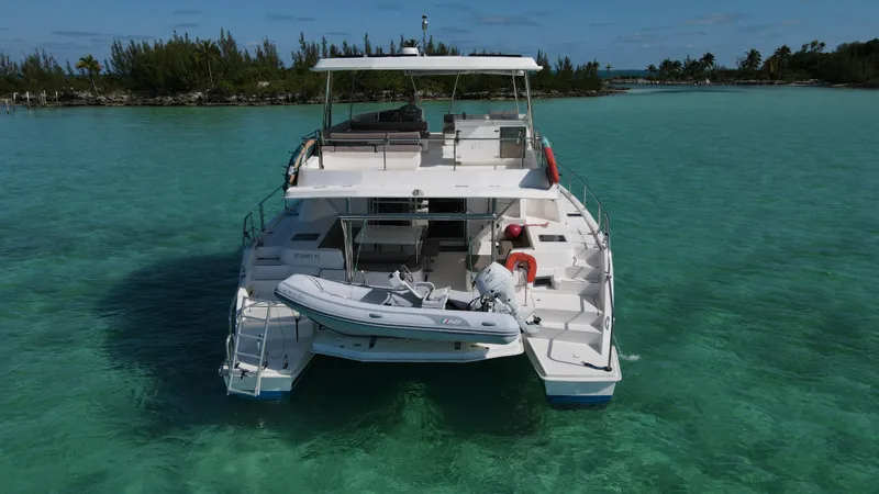 Salty Mitches Yacht Photos Pics Leopard 51 Powercat 2016 in clear turquoise waters, rear view with dinghy attached.