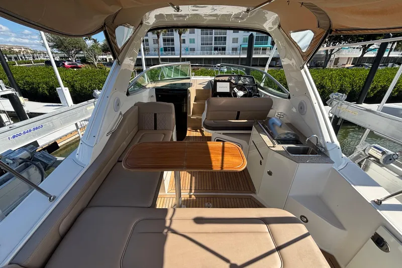 The Braciole Yacht Photos Pics 2017 Sea Ray 310 Sundancer interior with seating, table, and helm in marina setting.
