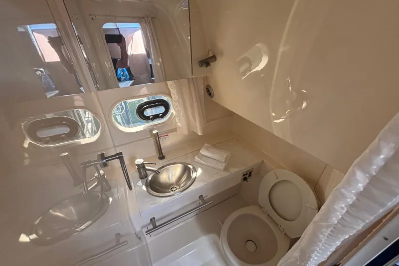 The Braciole Yacht Photos Pics 2017 Sea Ray 310 Sundancer bathroom with sink, toilet, and porthole windows.