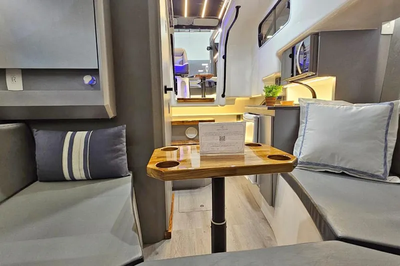  Yacht Photos Pics Modern interior of 2026 Hanover 327 RV with cozy seating and wooden table.