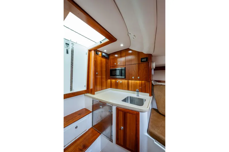 Seaclusion Yacht Photos Pics 2018 Albemarle 290 Express Fisherman cabin with wood cabinetry, sink, and microwave.