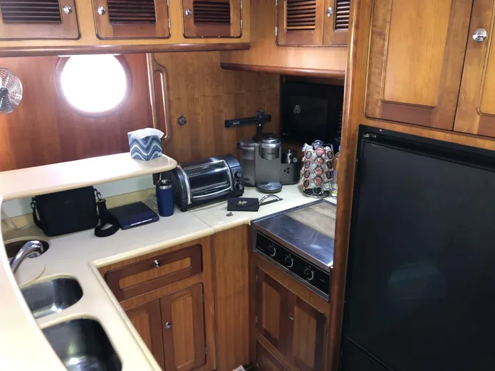Off The Grid Yacht Photos Pics 2001 Selene Ocean Trawler kitchen with wooden cabinets, appliances, and porthole window.