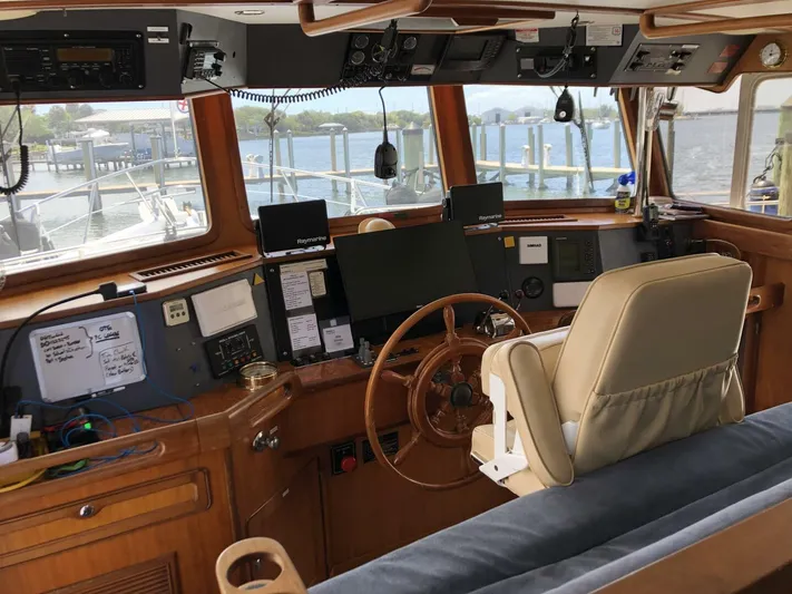 Off The Grid Yacht Photos Pics Interior of 2001 Selene Ocean Trawler's helm with navigation equipment and wooden steering wheel.
