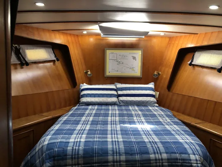 Off The Grid Yacht Photos Pics Cozy cabin interior of 2001 Selene Ocean Trawler with plaid bedding and wood paneling.