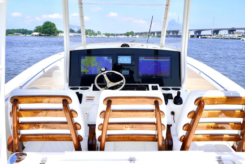  Yacht Photos Pics 2020 Cobia 350 Center Console boat with advanced navigation system and wooden seating on a calm waterway.