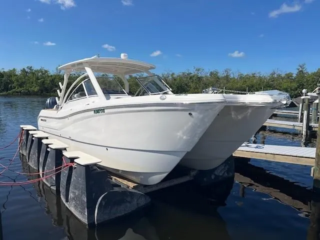  Yacht Photos Pics 2022 World Cat 296 DC boat docked on a sunny day, surrounded by water and trees.