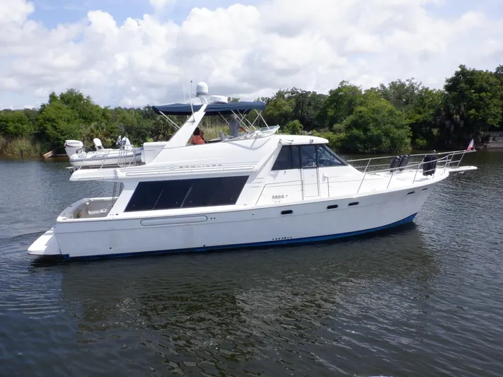 Epic Yacht Photos Pics 1998 Bayliner 4788 Pilothouse Motoryacht on calm water, surrounded by lush greenery.