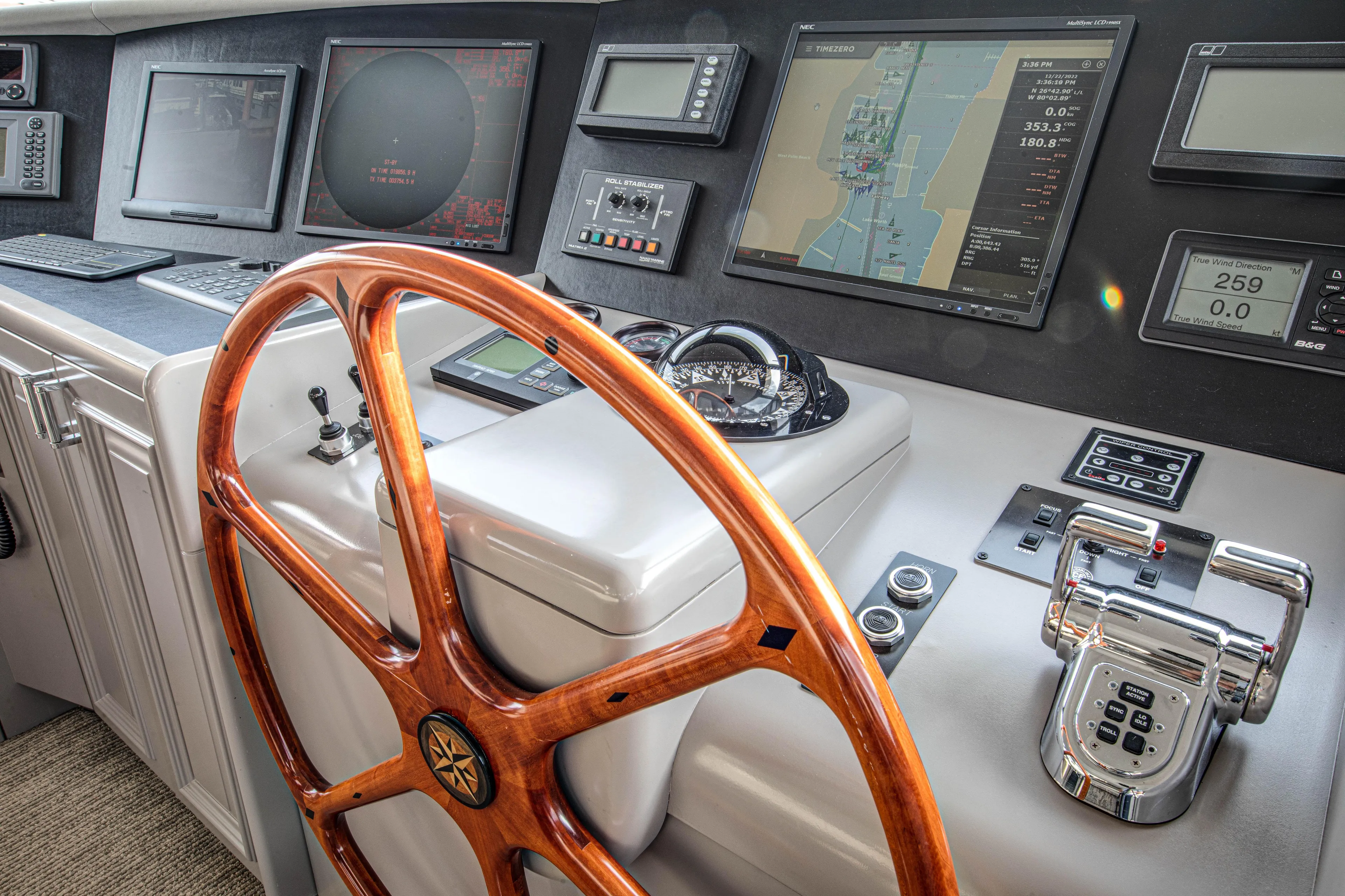 Spirit Yacht Photos Pics Control panel of a 2010 Westport 112 yacht with wooden steering wheel and navigation screens.