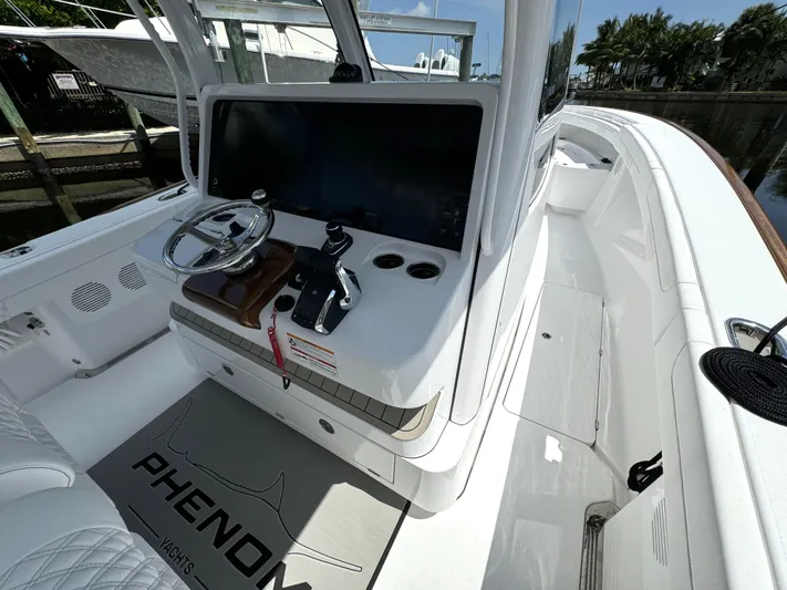  Yacht Photos Pics 2025 Phenom 37 boat cockpit with steering wheel, control panel, and branded mat.