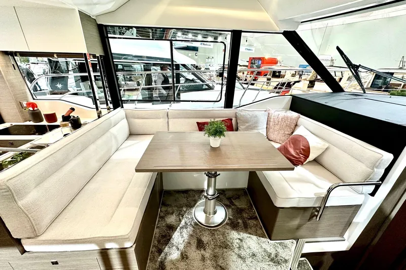  Yacht Photos Pics Interior of 2026 Jeanneau Merry Fisher 1295 Fly, featuring a cozy dining area with cushions.