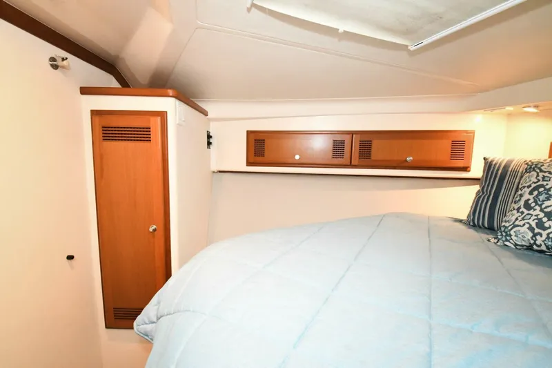 Vikingos Yacht Photos Pics Interior cabin of 2001 Cabo 35 Flybridge with bed and wooden storage cabinets.