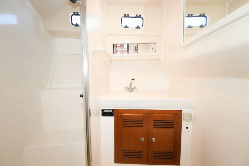 Vikingos Yacht Photos Pics 2001 Cabo 35 Flybridge bathroom with sink, mirror, and storage cabinet.