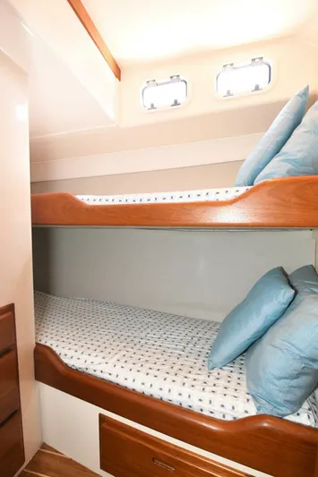 Vikingos Yacht Photos Pics Bunk beds in the 2001 Cabo 35 Flybridge cabin with blue pillows and porthole windows.