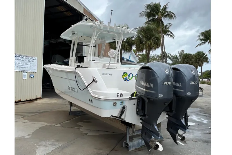 302-176 Brokerage Anthony Yacht Photos Pics 2018 Robalo R302 Center Console boat with twin Yamaha 300 engines, docked near palm trees.