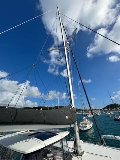 Solace Yacht Photos Pics 2020 Lagoon 42 sailboat with mast against blue sky and clouds in a marina.