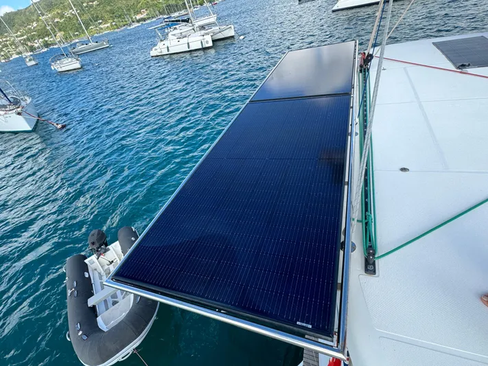 Solace Yacht Photos Pics 2020 Lagoon 42 catamaran with solar panels on deck, anchored in a scenic bay.