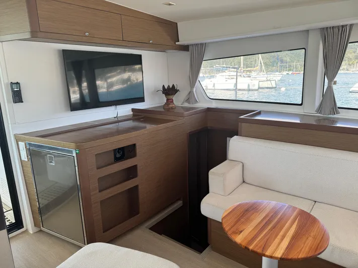 Solace Yacht Photos Pics Interior of 2020 Lagoon 42 yacht with modern seating, table, and window view of marina.