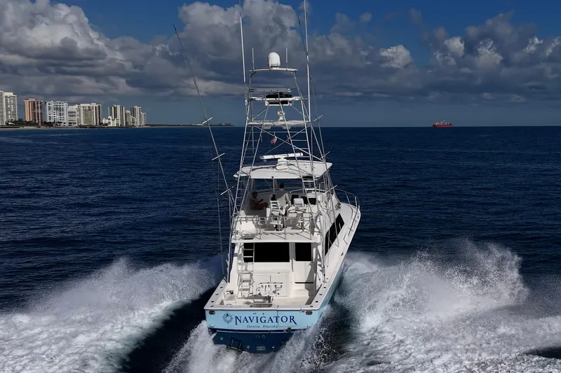 Navigator Yacht Photos Pics 1998 Viking 50 Convertible yacht cruising near city skyline under cloudy sky.
