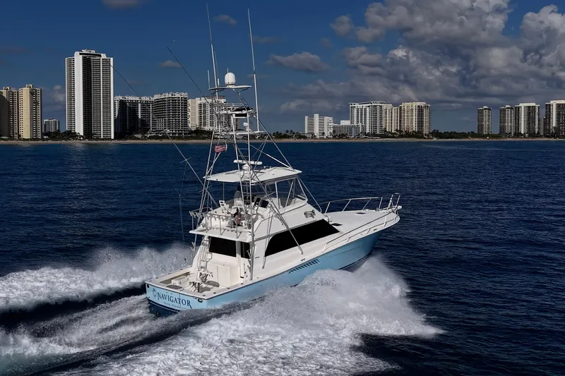 Navigator Yacht Photos Pics 1998 Viking 50 Convertible yacht cruising near city skyline on a sunny day.