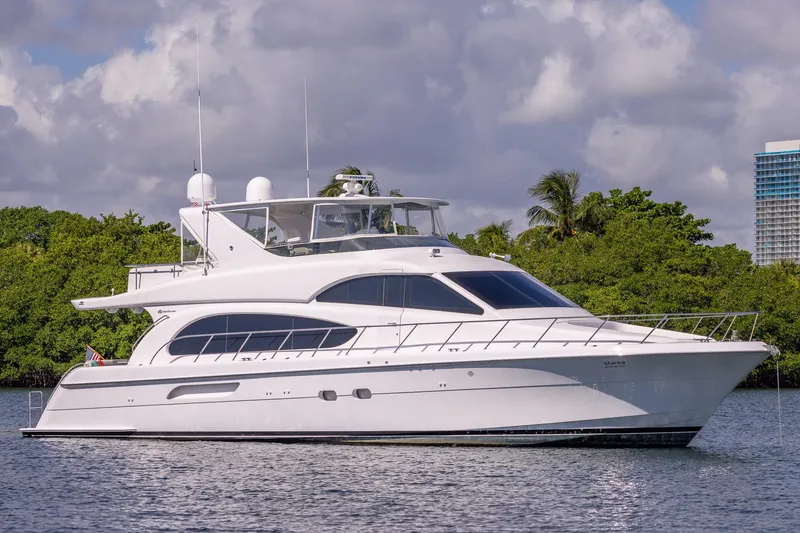 Starka Yacht Photos Pics 2009 Hatteras 64 Motor Yacht cruising on calm waters, surrounded by lush greenery.
