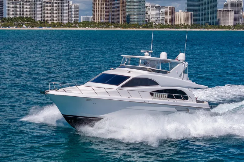 Starka Yacht Photos Pics 2009 Hatteras 64 Motor Yacht cruising near city skyline on blue ocean waters.