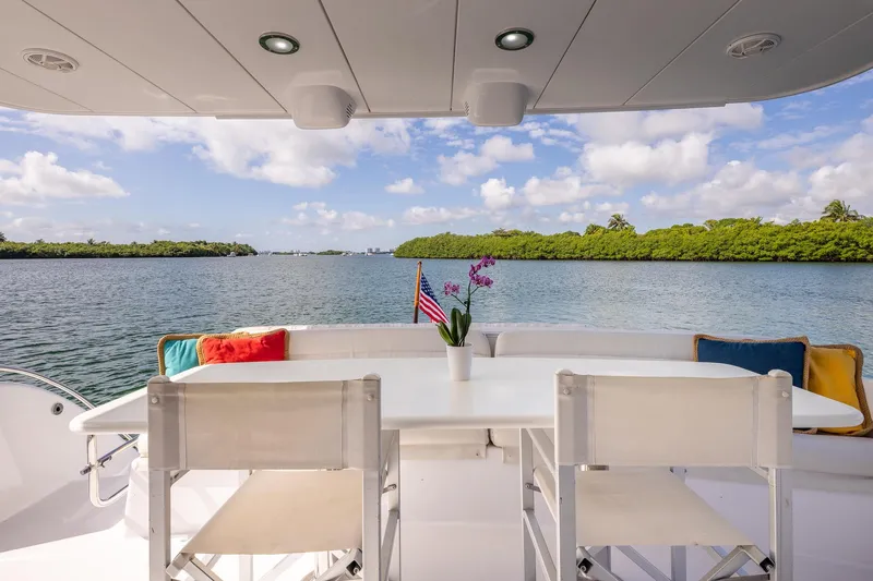 Starka Yacht Photos Pics 2009 Hatteras 64 Motor Yacht deck with dining area, scenic water view, and vibrant cushions.