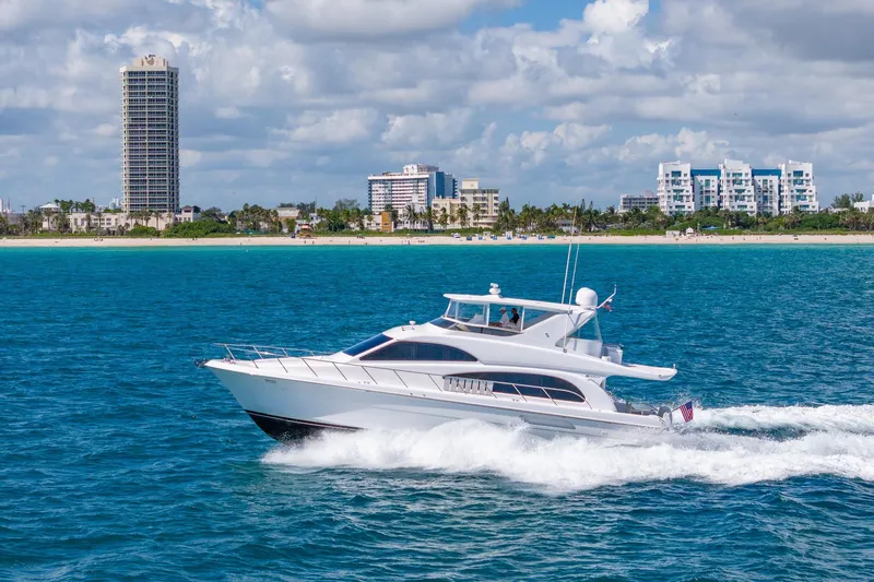 Starka Yacht Photos Pics 2009 Hatteras 64 Motor Yacht cruising near a coastal city skyline.