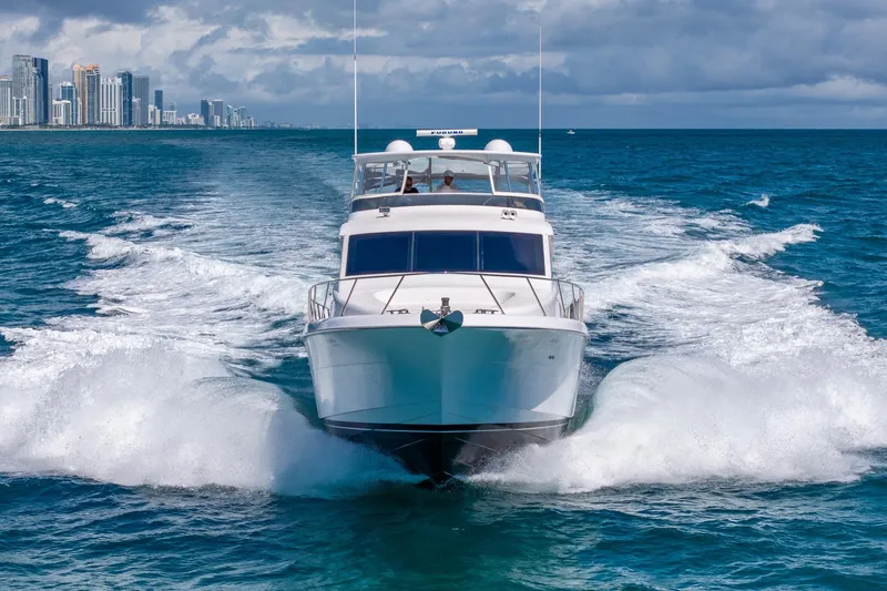 Starka Yacht Photos Pics 2009 Hatteras 64 Motor Yacht cruising near city skyline on open ocean.