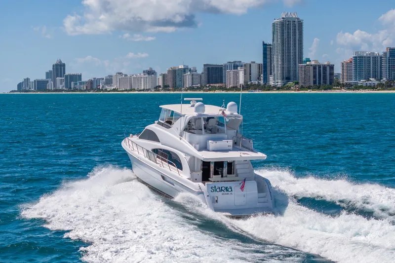 Starka Yacht Photos Pics 2009 Hatteras 64 Motor Yacht cruising near a city skyline on a sunny day.