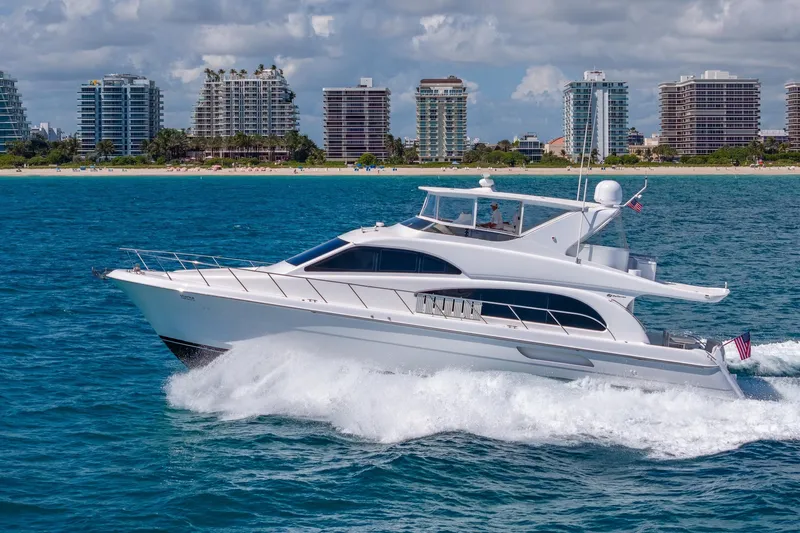 Starka Yacht Photos Pics 2009 Hatteras 64 Motor Yacht cruising near a coastal city skyline.