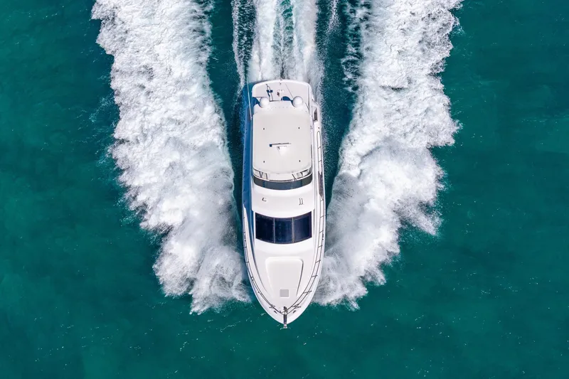Starka Yacht Photos Pics Aerial view of 2009 Hatteras 64 Motor Yacht cruising on turquoise water.